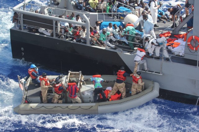 Distressed persons are transferred to a Maltese patrol vessel.